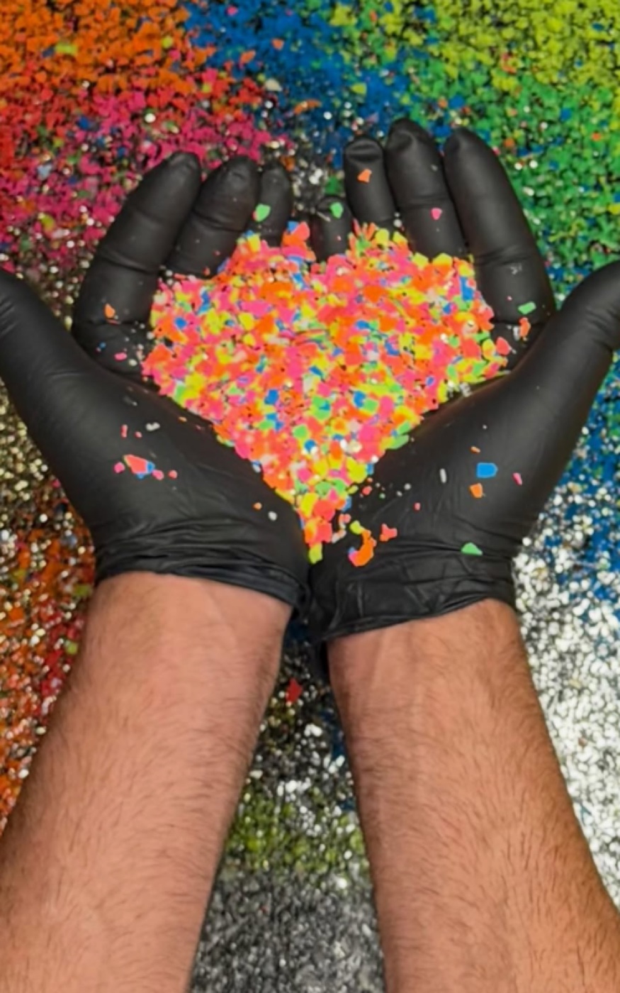 Hands holding a custom blend of colorful decorative floor flakes over a rainbow flake sample display